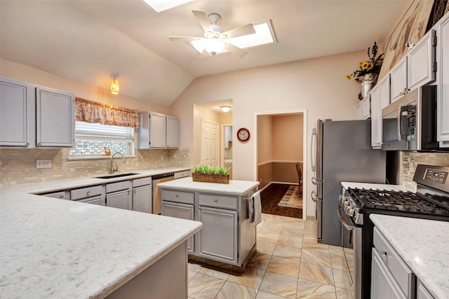 kitchen featuring vaulted ceiling, appliances with stainless steel finishes, sink, gray cabinetry, and a center island