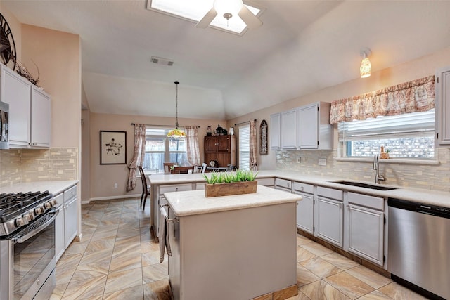 kitchen with sink, a center island, vaulted ceiling, pendant lighting, and stainless steel appliances