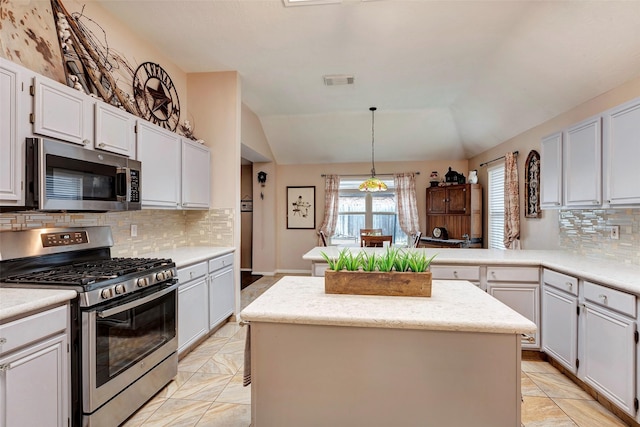 kitchen with vaulted ceiling, a kitchen island, pendant lighting, white cabinets, and stainless steel appliances