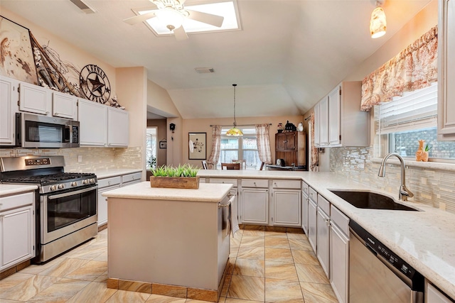 kitchen featuring stainless steel appliances, decorative light fixtures, sink, and white cabinets