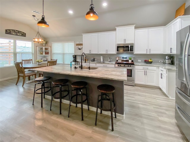 kitchen with visible vents, a sink, tasteful backsplash, stainless steel appliances, and vaulted ceiling