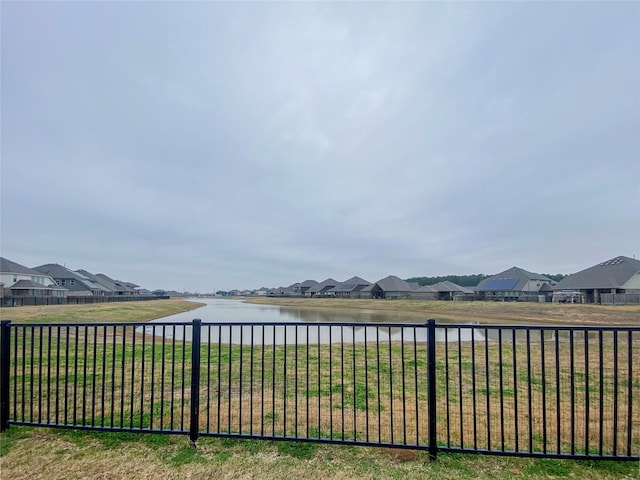 view of yard featuring a residential view, fence, and a water view