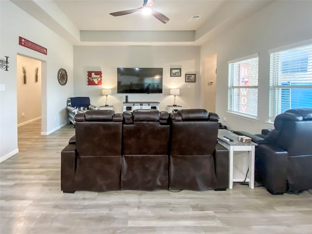 living area featuring baseboards, wood finished floors, plenty of natural light, and ceiling fan