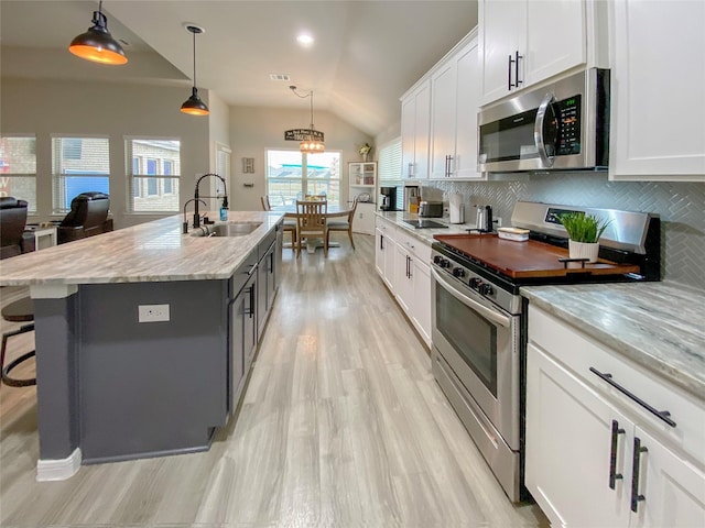 kitchen featuring tasteful backsplash, stainless steel appliances, lofted ceiling, and a sink