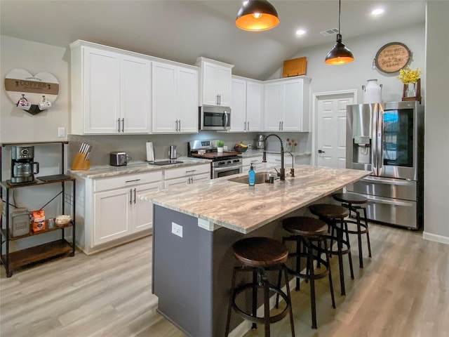 kitchen featuring stainless steel appliances, a kitchen breakfast bar, tasteful backsplash, and light wood-style flooring