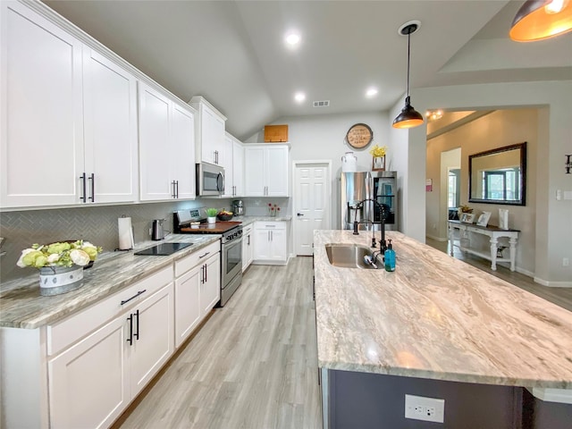 kitchen featuring a sink, backsplash, appliances with stainless steel finishes, and a kitchen island with sink