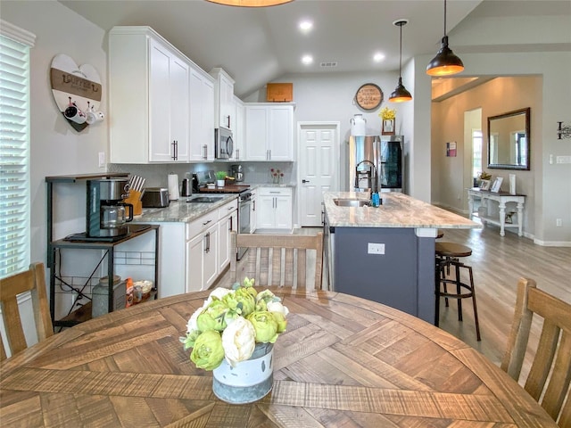 kitchen with tasteful backsplash, a sink, a breakfast bar, appliances with stainless steel finishes, and a kitchen island with sink