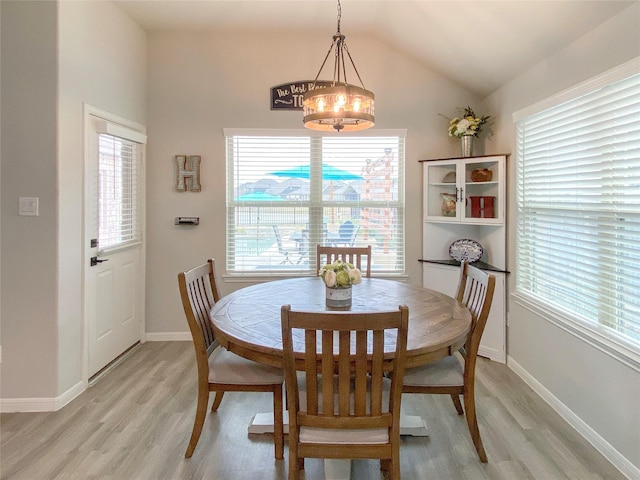 dining area with baseboards, light wood finished floors, a chandelier, and vaulted ceiling