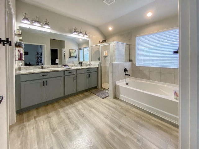 full bath with a garden tub, a healthy amount of sunlight, wood finished floors, and a shower stall