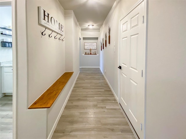 corridor with light wood-type flooring and baseboards