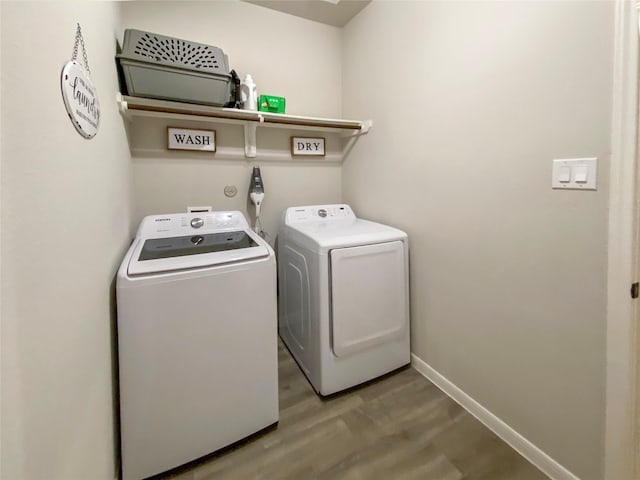 laundry area with washer and clothes dryer, laundry area, baseboards, and wood finished floors