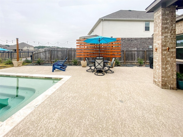 view of swimming pool with outdoor dining area, a patio, and a fenced backyard