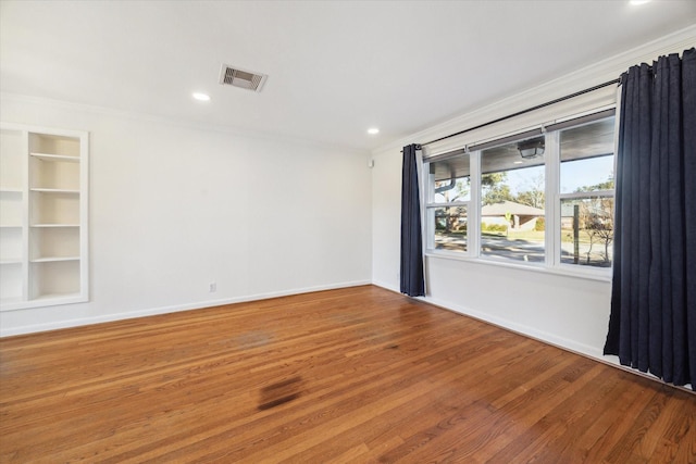 unfurnished room with crown molding, wood-type flooring, and built in features