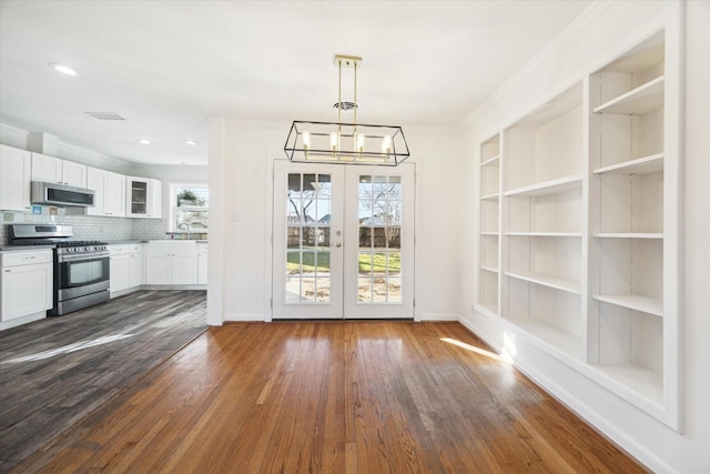 unfurnished dining area featuring dark wood-type flooring, sink, built in features, and a chandelier