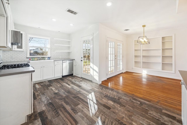 kitchen featuring dark wood-type flooring, dishwasher, white cabinetry, decorative backsplash, and decorative light fixtures