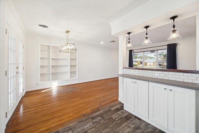 kitchen with hanging light fixtures, built in features, white cabinets, and dark hardwood / wood-style flooring