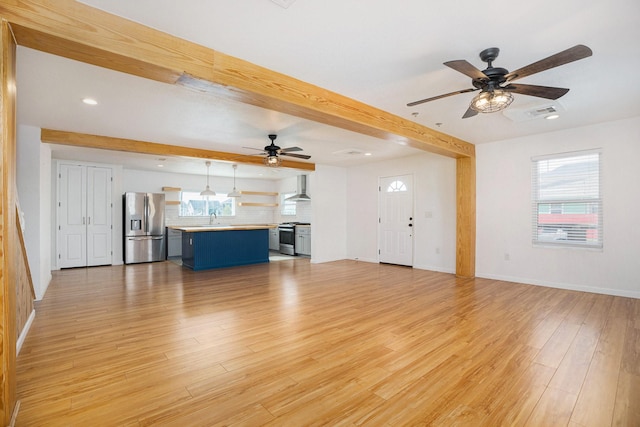 unfurnished living room featuring beamed ceiling, ceiling fan, light hardwood / wood-style floors, and sink