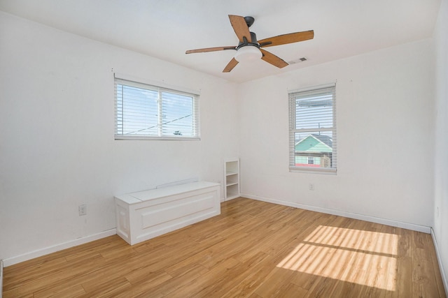 unfurnished room with ceiling fan, a wealth of natural light, and light wood-type flooring