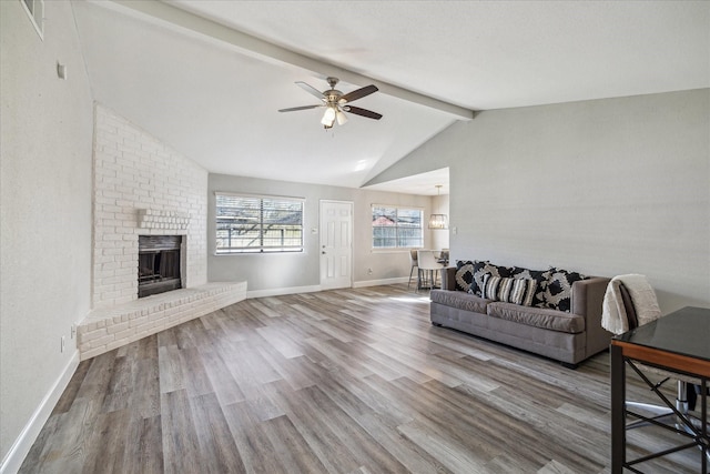 living room featuring vaulted ceiling with beams, hardwood / wood-style flooring, a brick fireplace, and ceiling fan