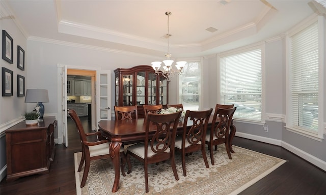 dining room with crown molding, dark hardwood / wood-style floors, an inviting chandelier, and a tray ceiling