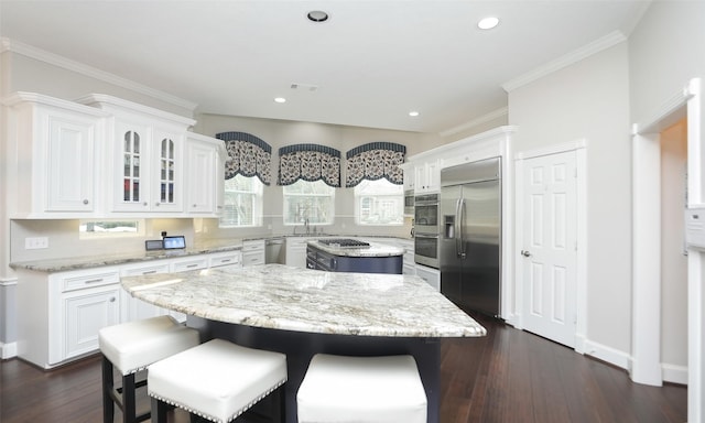 kitchen featuring light stone countertops, appliances with stainless steel finishes, white cabinets, and a kitchen island