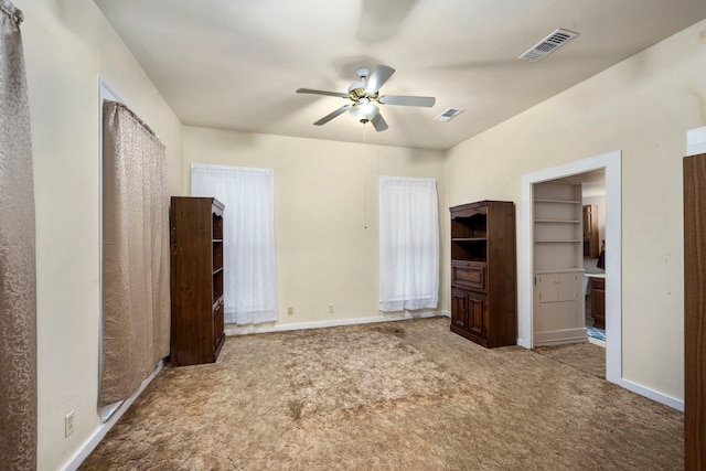 unfurnished bedroom featuring a walk in closet, carpet, and ceiling fan