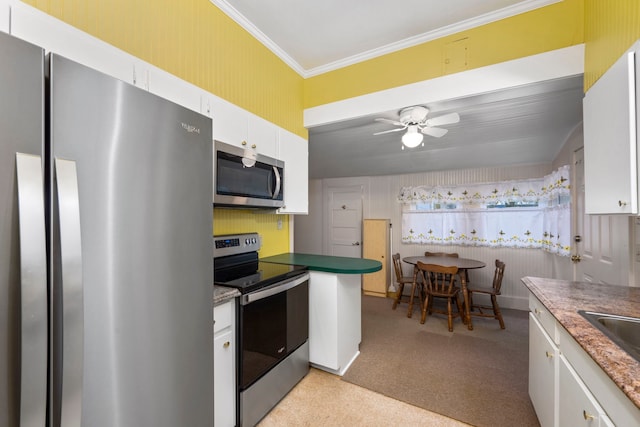 kitchen featuring appliances with stainless steel finishes, white cabinets, ornamental molding, light colored carpet, and ceiling fan