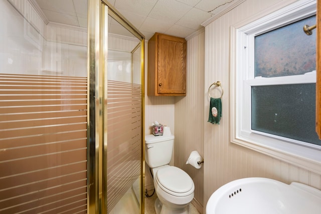 bathroom featuring crown molding, a shower with shower door, and toilet