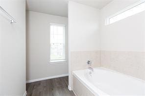 bathroom featuring hardwood / wood-style flooring, a healthy amount of sunlight, and tiled bath