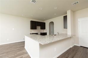 kitchen with light stone countertops, hardwood / wood-style floors, and kitchen peninsula