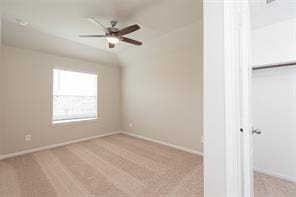 carpeted spare room featuring lofted ceiling and ceiling fan