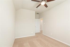 empty room featuring vaulted ceiling, light colored carpet, and ceiling fan