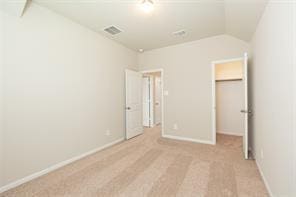 unfurnished bedroom featuring lofted ceiling, a spacious closet, and a closet