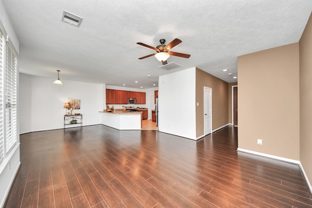 unfurnished living room with dark wood-type flooring, ceiling fan, and a textured ceiling