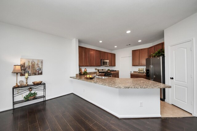 kitchen featuring appliances with stainless steel finishes, sink, kitchen peninsula, and hardwood / wood-style floors