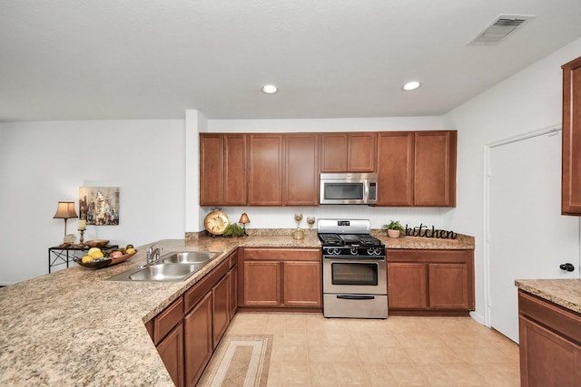 kitchen with sink, stainless steel appliances, and light stone countertops