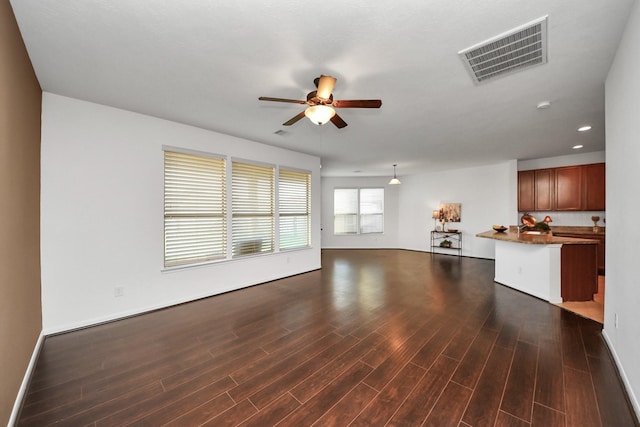 unfurnished living room featuring dark wood-type flooring and ceiling fan