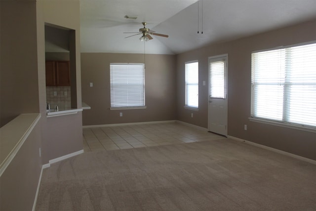 empty room with lofted ceiling, light tile patterned floors, and a wealth of natural light