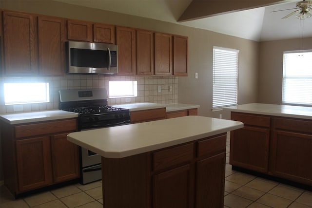 kitchen featuring tasteful backsplash, appliances with stainless steel finishes, a kitchen island, and light tile patterned floors