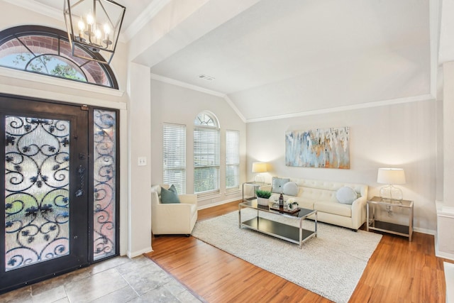 foyer with a notable chandelier, vaulted ceiling, hardwood / wood-style floors, and ornamental molding