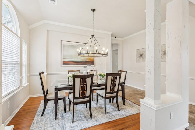 dining area with wood-type flooring, vaulted ceiling, ornamental molding, and a chandelier