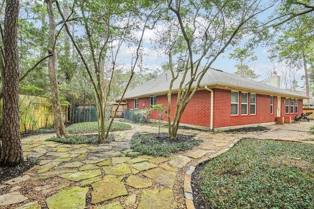 exterior space with brick siding, a chimney, and fence