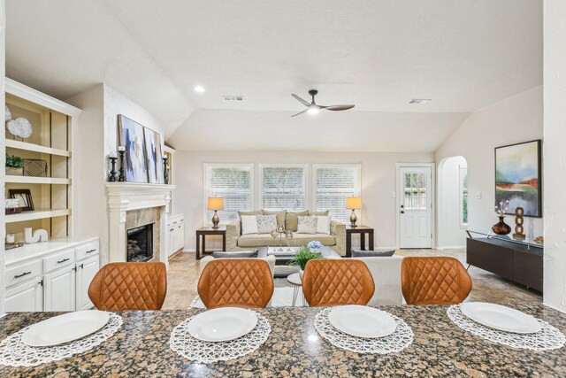 dining area featuring lofted ceiling, a fireplace, built in features, and ceiling fan