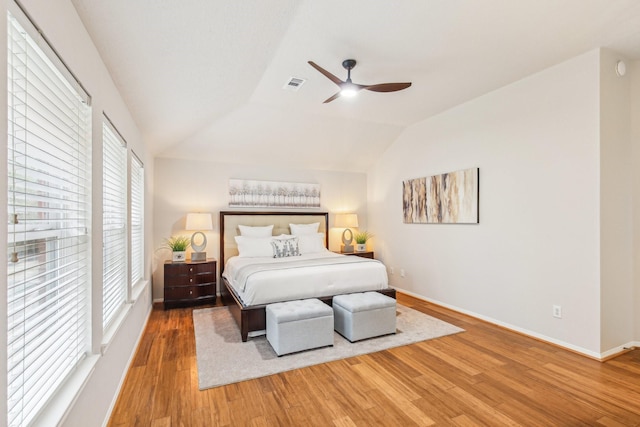 bedroom featuring visible vents, baseboards, lofted ceiling, and wood finished floors