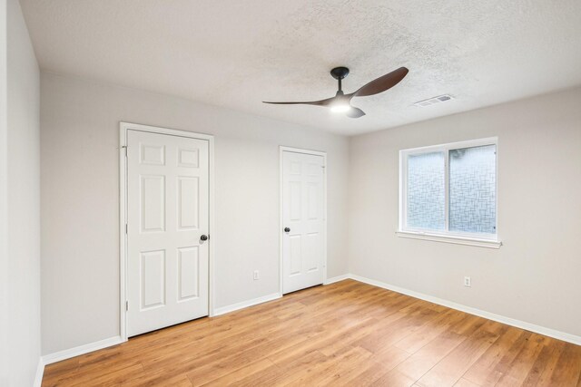 unfurnished bedroom with visible vents, a textured ceiling, baseboards, and light wood-style floors