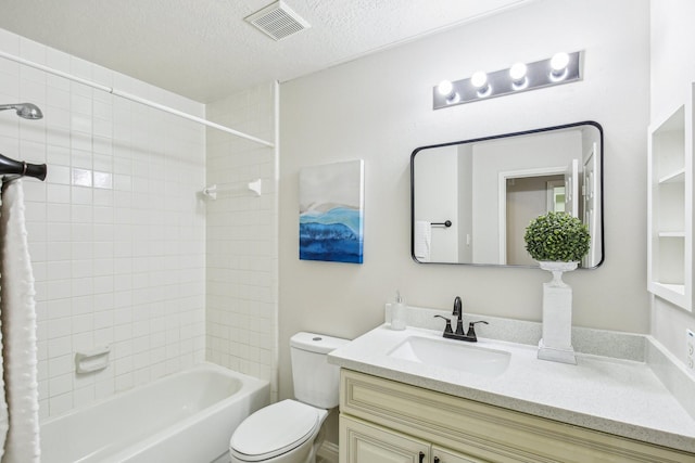 full bathroom featuring vanity, tiled shower / bath, a textured ceiling, and toilet