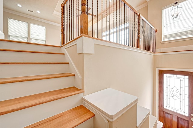 stairway with ornamental molding and a high ceiling