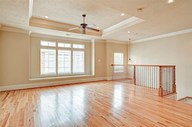 unfurnished room with ornamental molding, light hardwood / wood-style floors, and a tray ceiling