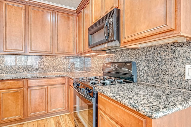 kitchen featuring tasteful backsplash, light stone countertops, light hardwood / wood-style floors, and black appliances