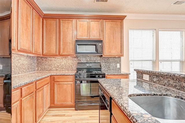 kitchen featuring light wood-type flooring, decorative backsplash, ornamental molding, black appliances, and a textured ceiling